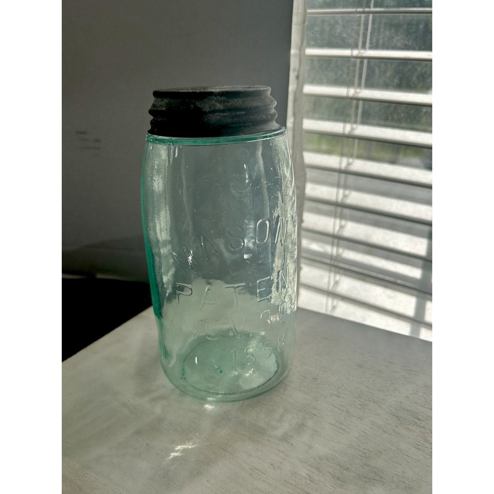 Antique Mason's Patent Nov. 30th 1858 quart jar — aqua glass with zinc lid and visible seed bubbles, front view