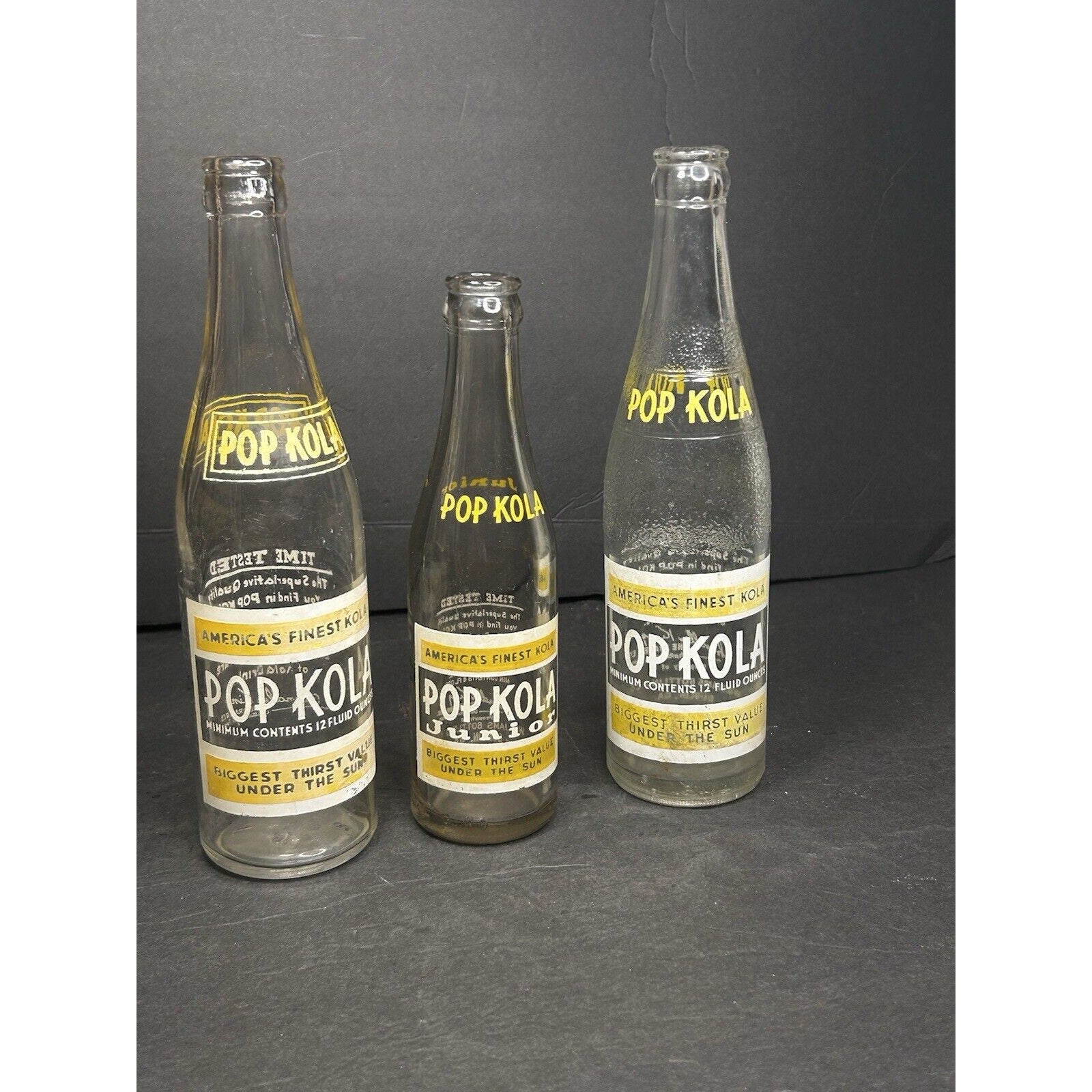 Antique Pop Kola bottles label close-up — applied color label detail showing yellow script lettering