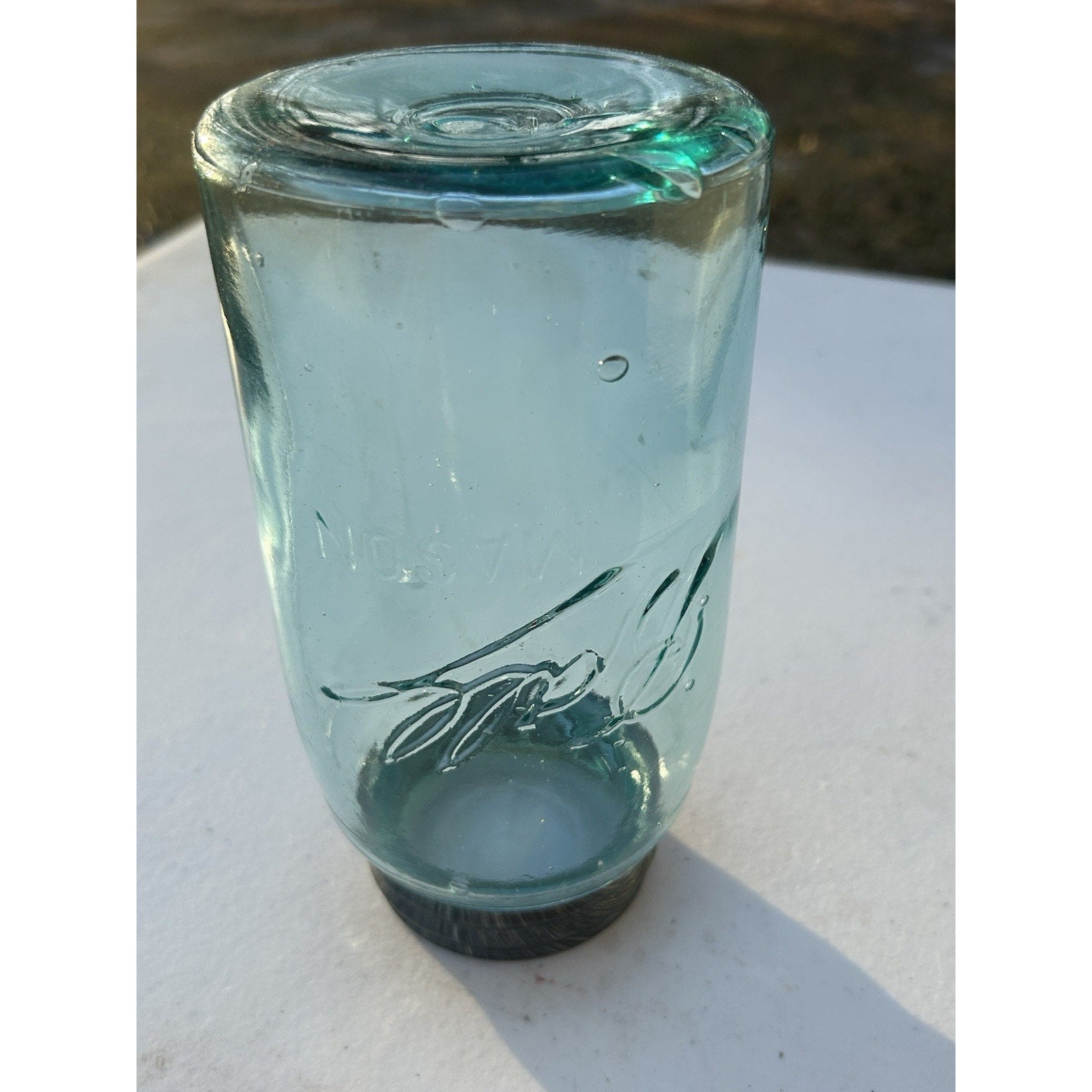 Ball Triple-L quart jar light through aqua glass — seed bubbles visible throughout, early 20th century glass