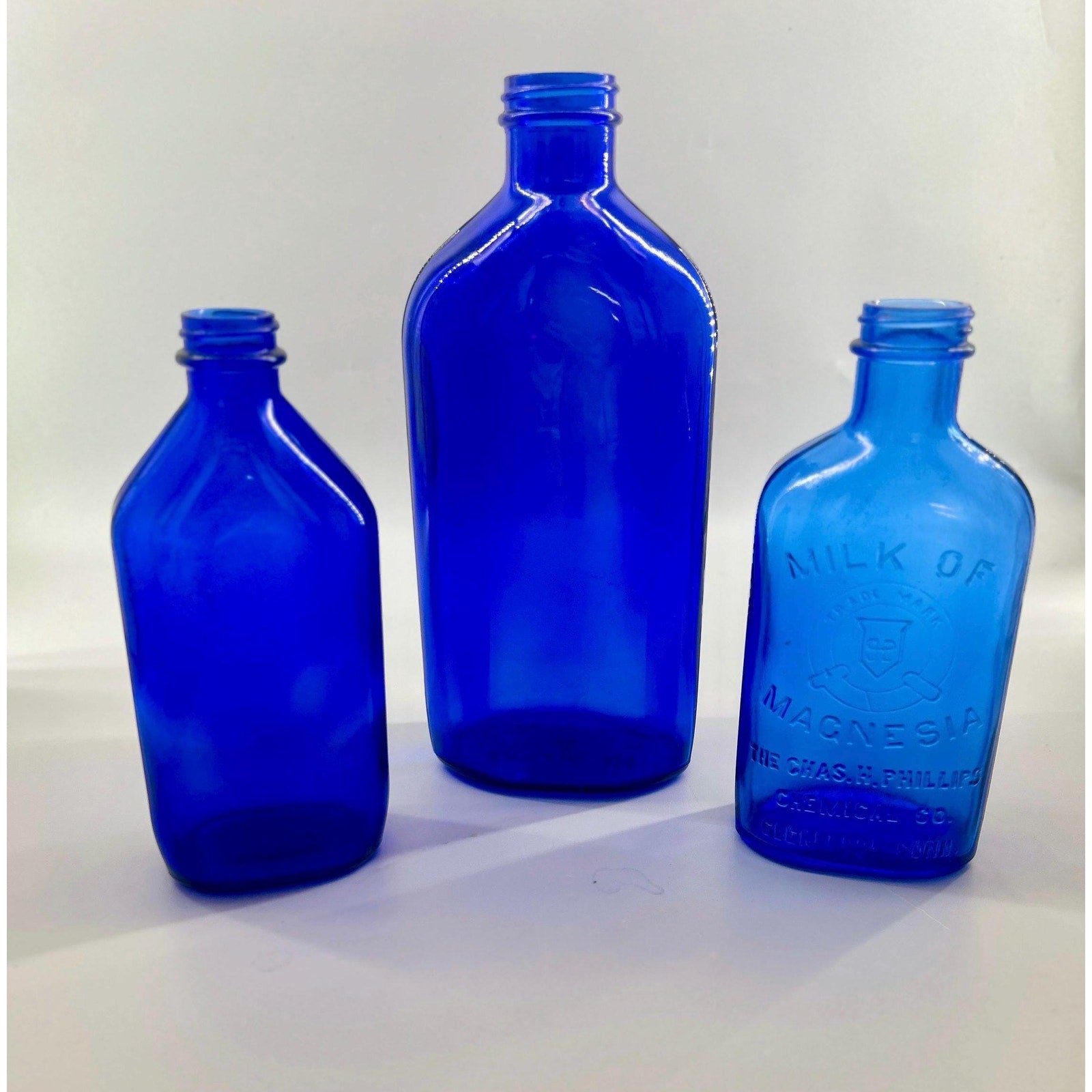 Lot of three antique cobalt blue apothecary bottles — Phillips Milk of Magnesia with two pharmacy bottles — blue glass collection