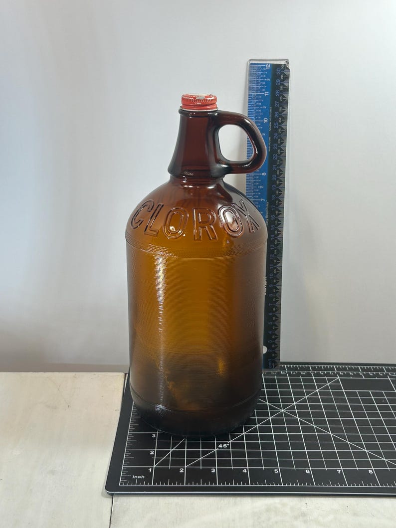 Smaller jug beside a vertical ruler on a gridded measurement mat.