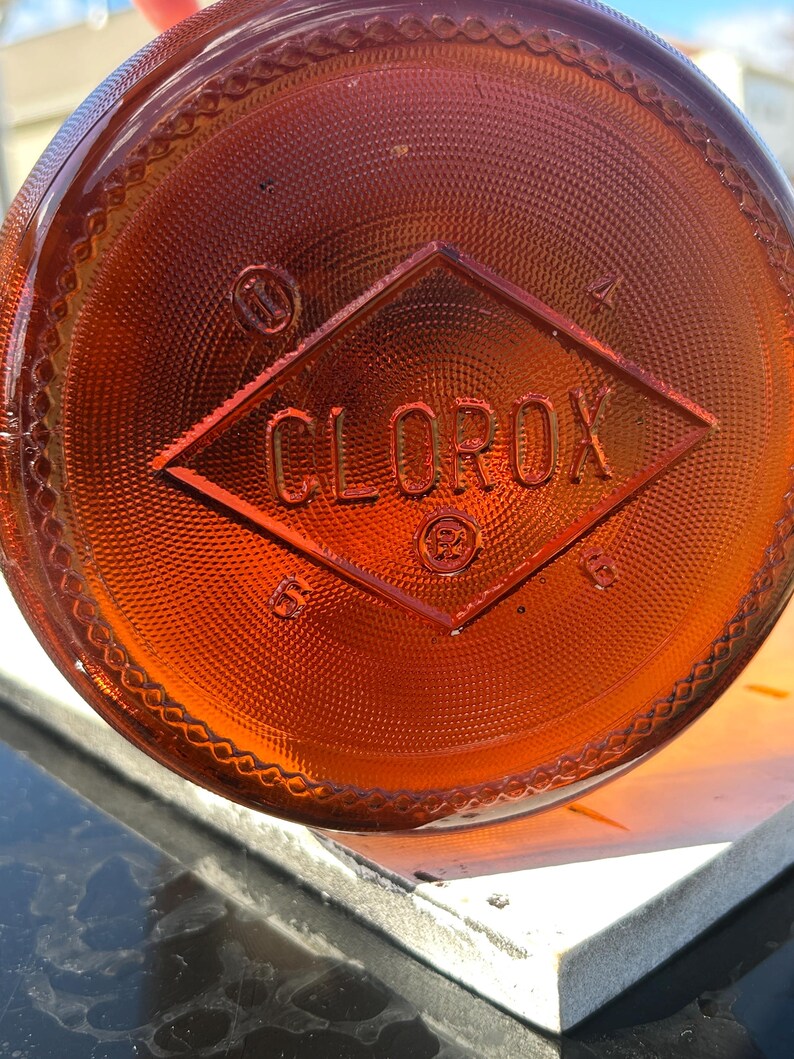 Bottom close-up showing the molded Clorox diamond mark on amber glass.
