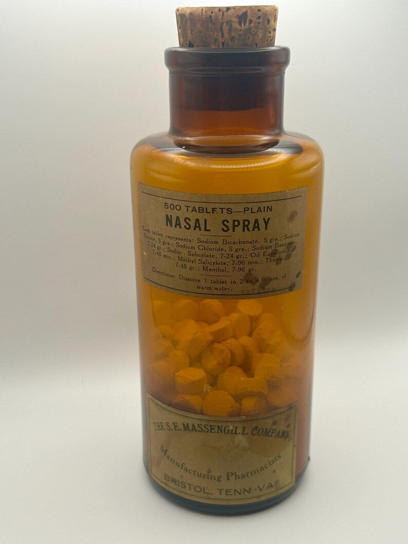 May include: An amber glass bottle labeled "500 TABLETS-PLAIN NASAL SPRAY" with a cork stopper. The bottle contains numerous yellow tablets. The label includes ingredient information and the manufacturer's name, "THE S.E. MASSENGILL COMPANY."