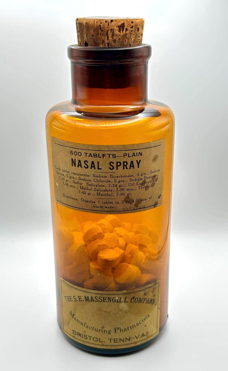 May include: An antique amber glass bottle labeled "NASAL SPRAY" with a cork stopper. The label indicates the contents are 500 tablets and lists ingredients. The bottle is filled with orange tablets and has a label from The S.E. Massengill Company.