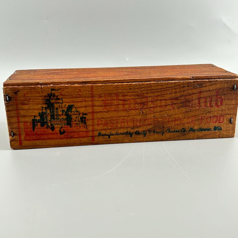 May include: A rectangular wooden box with a reddish-brown finish. The box features faded red text and a graphic of a castle on one side. The text includes the words "White Club" and "Pasteurized Cheese Food".