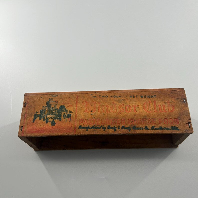 May include: A vintage wooden box with the words "Windsor Club" and "Pasteurized Cheese Food" printed on the front. The box has a faded orange and brown color scheme with a green illustration of a building.