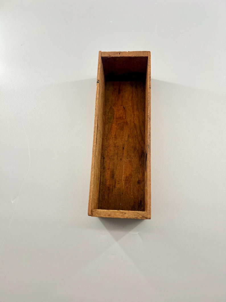 May include: A rectangular wooden box with a natural wood grain finish. The box is open at the top and appears to be empty. The wood has a warm, brown tone, and the box is set against a white background.