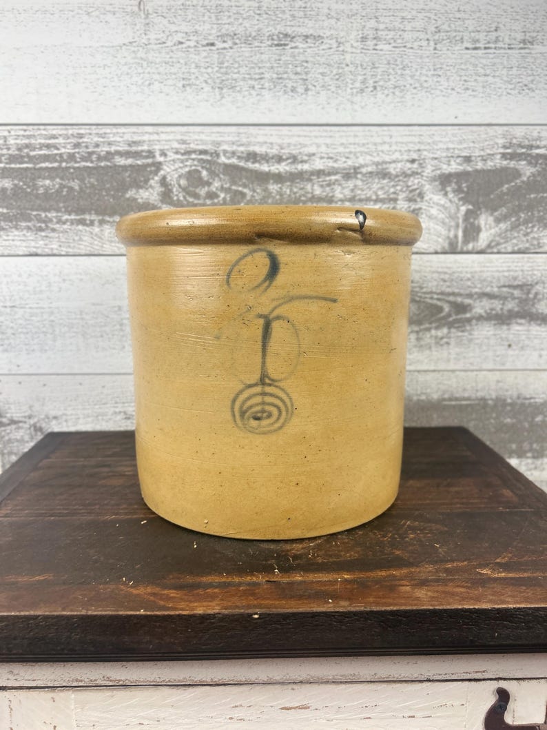 Full crock photographed from farther away against a weathered white background.