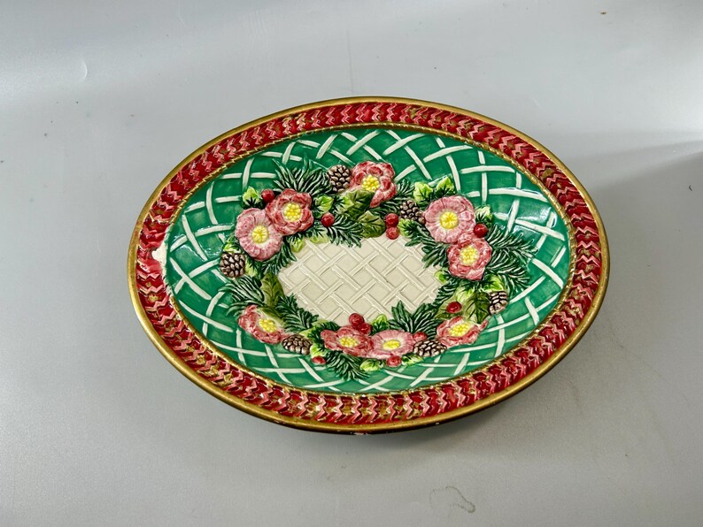 Top view of the bowl with pink flowers, greenery, pinecones, and red patterned rim.