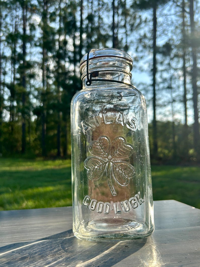 Front outdoor view of clear Atlas Good Luck jar showing the embossed four-leaf clover.