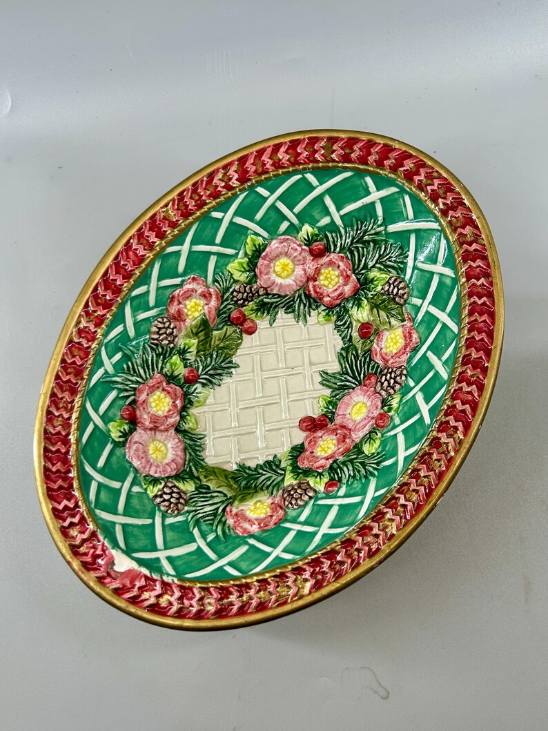 Three-quarter top view of the oval bowl with floral wreath centered inside.