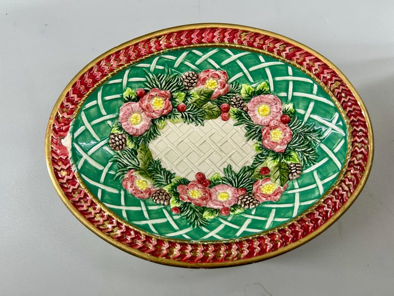 Angled overhead view showing the oval bowl's green field and central Christmas wreath design.
